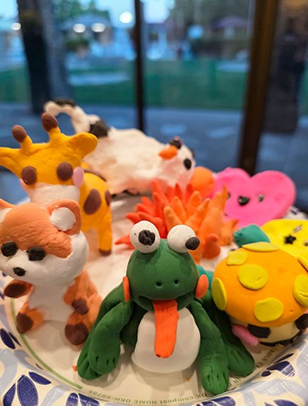 A plate of modelling-clay animals made at a craft class: a frog, a giraffe, a fox and a hedgehog.