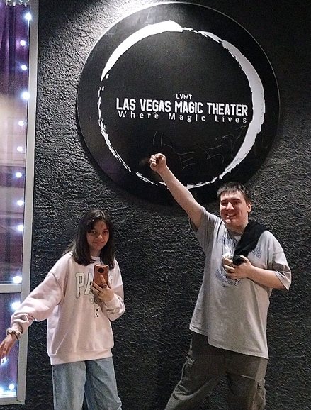 Two members outside the Las Vegas Magic Theater, one with a fist raised.