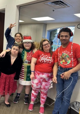 Five members in festive holiday sweaters posing together with big smiles.