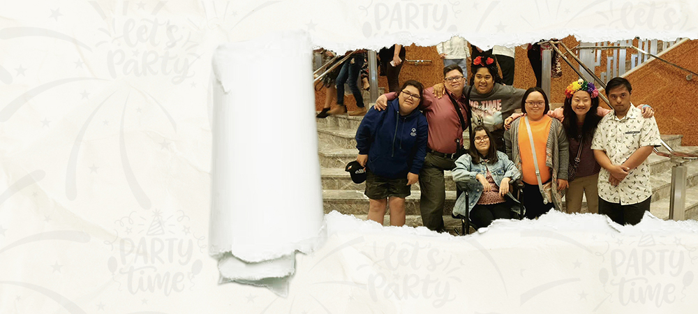 A group of members posing together at the foot of a staircase, seen through a tear in a sheet of paper.